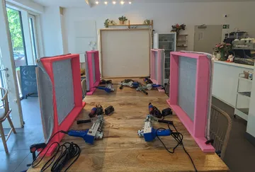 Pink honey harvesting boxes on wooden table.