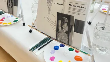 Staffelei mit der Porträtskizze von Frida Kahlo, Farben unten.