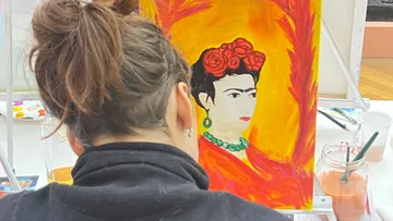 Person painting a portrait in a studio.