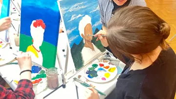 People painting at easels in a studio.