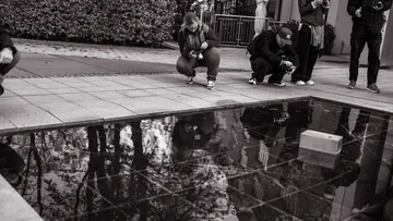 Leute, die draußen einen reflektierenden Pool fotografieren.