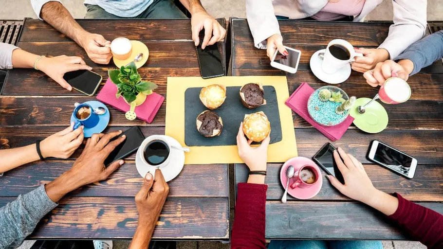 People with coffee and smartphones around a table.