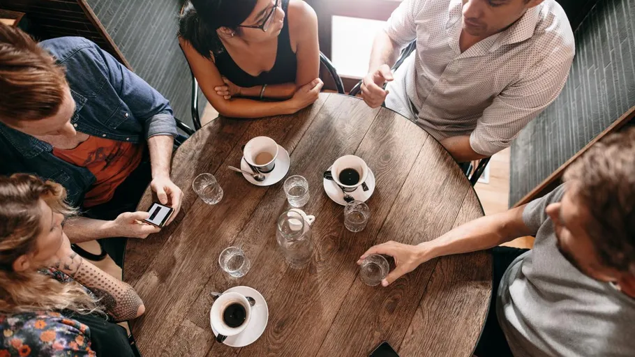 People seated around table with coffee cups.