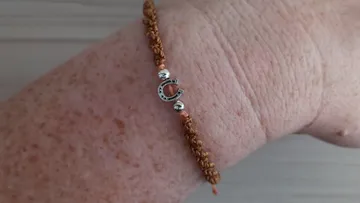 Brown knotted bracelet with silver horseshoe charm.