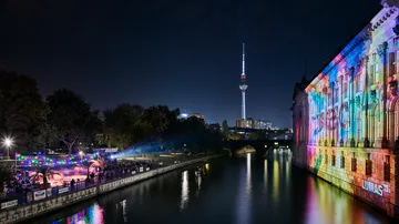 Gebäude mit bunten Lichtern am Fluss bei Nacht.