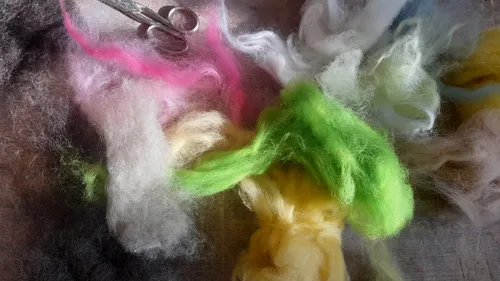 Colorful wool fibers with scissors on table.