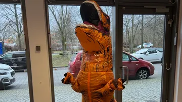 Aufblasbares Dinosaurierkostüm drinnen in der Nähe der Glastür.