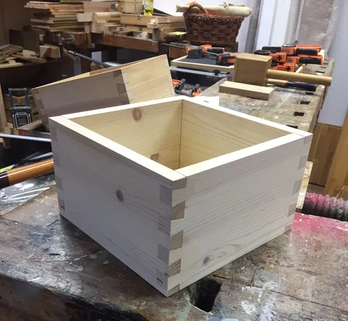 Wooden box with dovetail joints, workshop background.