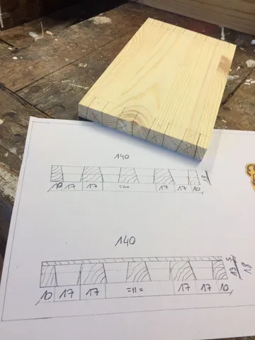 Holzbrett mit Maßzeichnungen auf Papier.