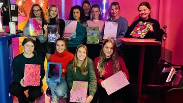 Gruppe von elf Personen, die bunte Notizbücher in der Hand halten.