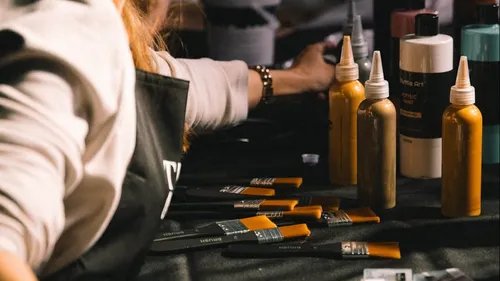 Artist using brushes and paint bottles on table.