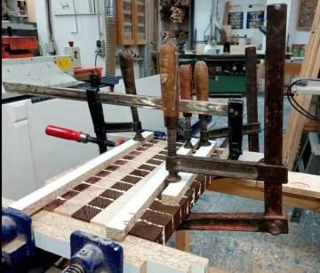 Holzstücke, die in einer Werkstatt zum Kleben eingespannt wurden.
