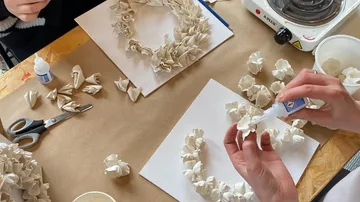 Hands assembling clay roses on boards.