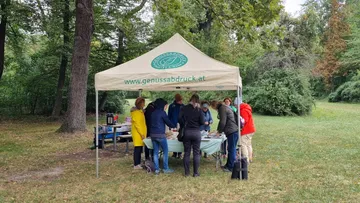 People gathered under tent in park.