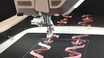 Stickmaschine zum Sticken eines rosafarbenen Blumenmusters.