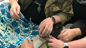 Leute, die einen blau gemusterten Stoff nähen.