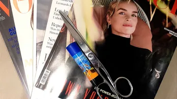 Schere und Klebestift auf dem Zeitschriftenstapel.