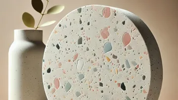 Round terrazzo slab beside matte vase.
