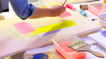 Person painting with brush on canvas.