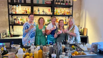 Fünf Frauen halten Getränke in einer Bar.