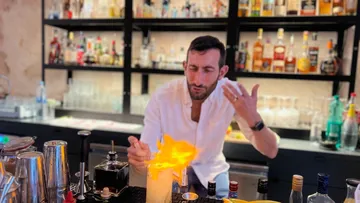 Barkeeper zündet Cocktail an, Bar-Hintergrund.