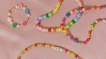 Bunte Perlenarmbänder auf rosafarbenem Stoff.
