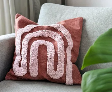 Textured pillow with pink pattern on sofa.