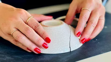 Hände reparieren kaputte Schüssel auf dem Tisch.