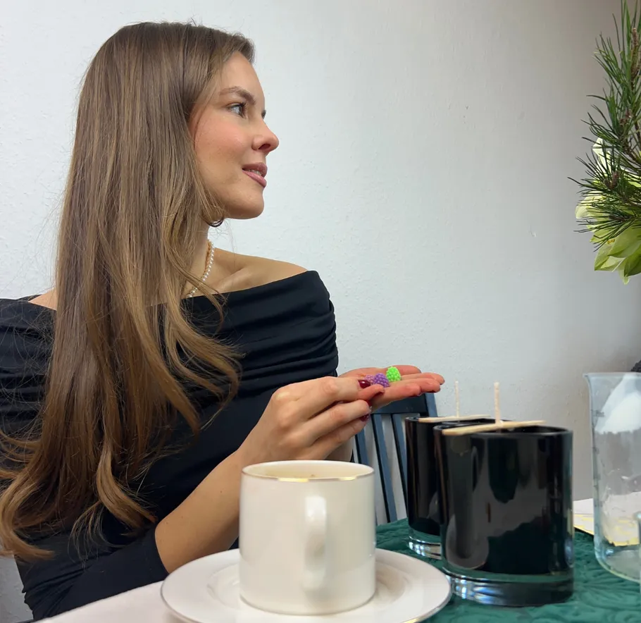 Frau hält bunte Beeren in der Nähe von Bechern auf dem Tisch.
