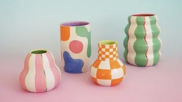 Bunte geometrische Vasen auf pastellfarbenem Hintergrund.
