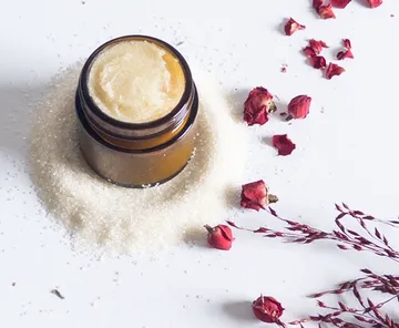 Jar with cream on sugar, rose petals.