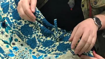 Person, die blauen geblümten Stoff drinnen hält.