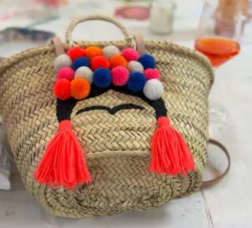 Woven basket with colorful pom-pom decorations.