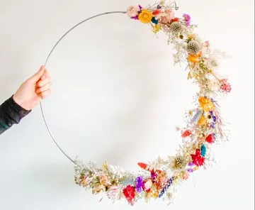 Hand holding floral-decorated wire hoop.