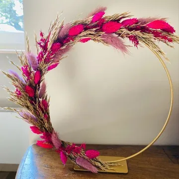 Floral wreath with pink accents on stand.