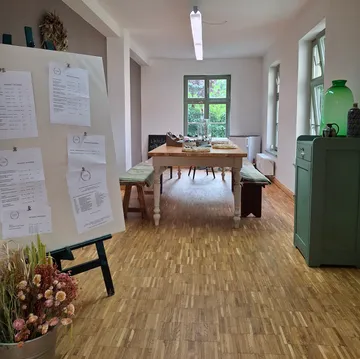Zimmer mit Holzboden und Holzbrett, Tisch mit Stühlen.