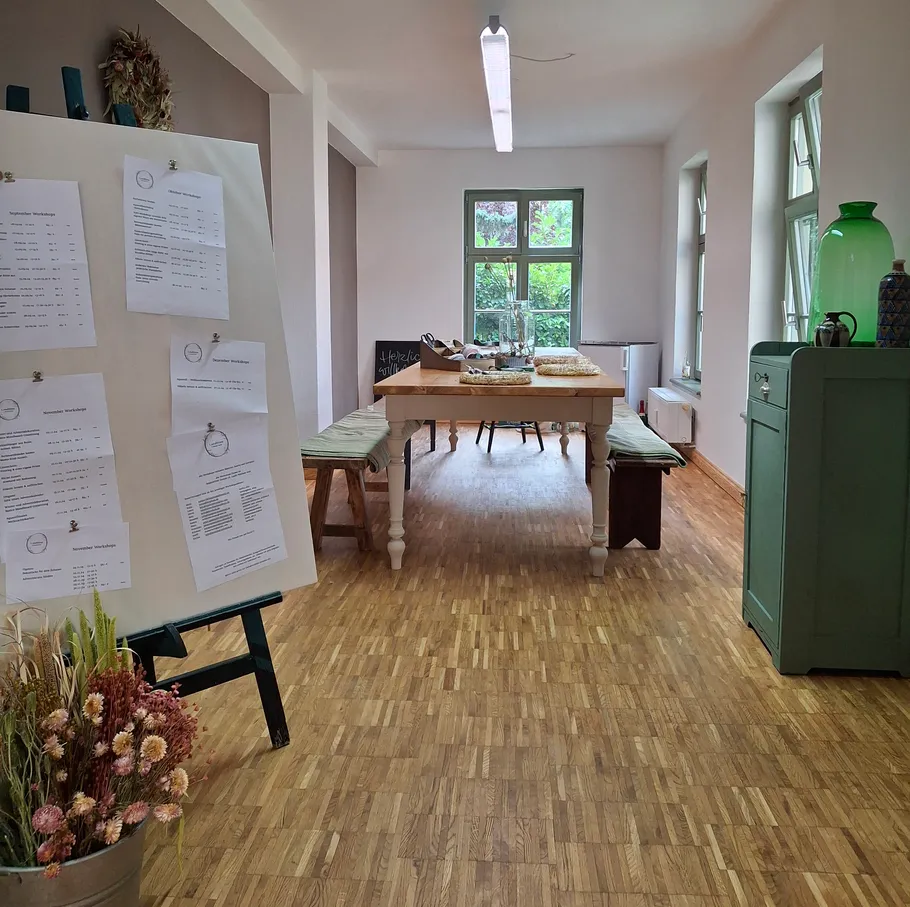 Room with wooden floor and board, table with chairs.