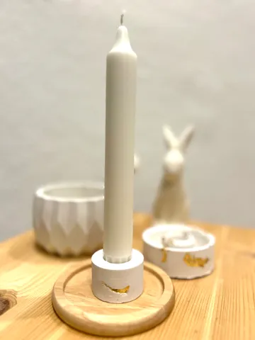 White candle in holder on wooden table.