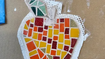 Bunter Mosaikapfel auf Kartonoberfläche.