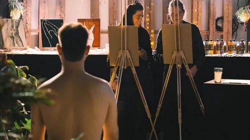 Artists sketching a male model indoors.