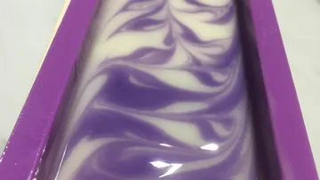 Purple and white swirled soap in mold.