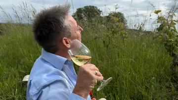 Man sipping wine in grassy field.