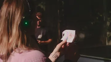 Woman wearing headphones holds decorated paper