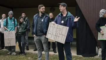 Gruppe, die draußen Protestschilder hochhält.