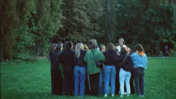 Gruppe mit Kopfhörern steht zusammen im Park.