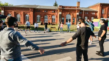 Leute, die Kopfhörer tragen und vor einem Backsteingebäude tanzen.