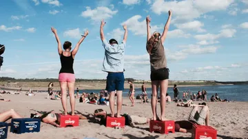 Leute, die auf Boxen am Strand stehen.