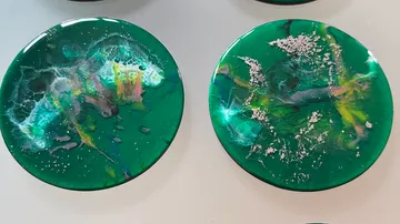 Zwei runde Untersetzer aus grünem Harz mit abstrakten Motiven.