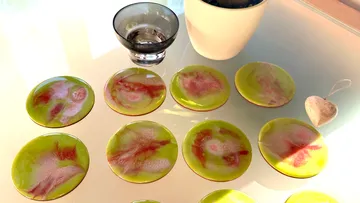 Untersetzer aus Keramik in Grün-Rosa auf einem Glastisch