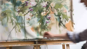 Person, die Blumenkunst auf Leinwand malt